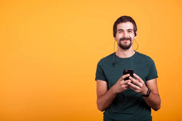 Feliz hombre sonriente con auriculares al escuchar música en su teléfono inteligente —  Fotos de Stock