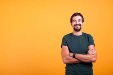 Kameraya gülümseyen yakışıklı adam kollarını ile geçti