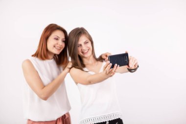 Bir selfie alarak portresi iki güzel genç kadın, bir Dişileştirilmiş ve kahverengi saçlı,