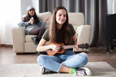 İki kız kardeş, küçük olan küçük bir oynuyor gitar öne, diğeri arkaya şarkı