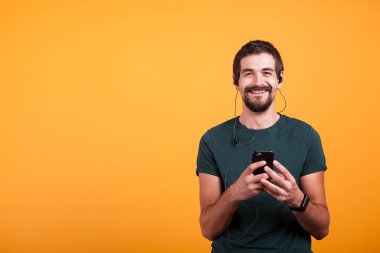 Müzik dinleme kulaklıklar ile mutlu gülümseyen adam onun Smartphone
