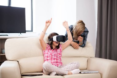 Anne bir sanal gerçeklik kulaklık giyen kızı yanında oturan oturma odasında