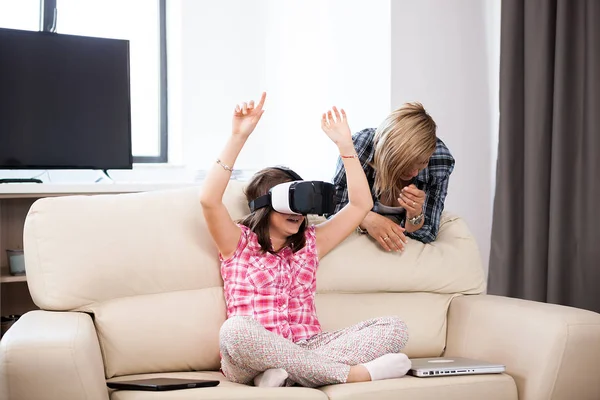 Matka v obývacím pokoji sedí vedle její dcera, která má na sobě soupravu pro virtuální realitu — Stock fotografie