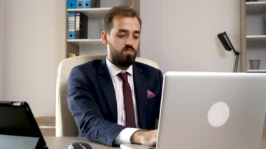 Ofis multitasking. Dizüstü bilgisayarda çalışan genç girişimci