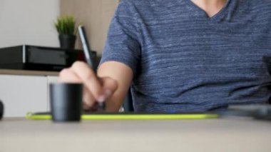 Grafik tasarımcı dijital tablete çizerken müzik dinliyor