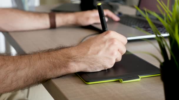 Чоловік малює рукою за допомогою цифрового планшета — стокове відео