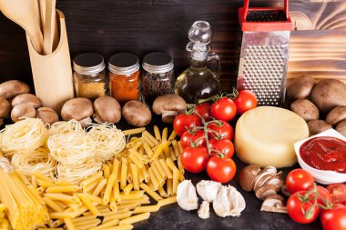 Pişmemiş çiğ makarna sebze yanındaki rustik arka plan üzerinde