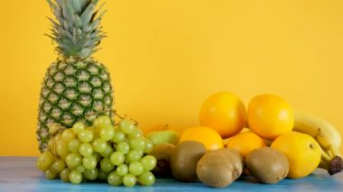Portakal, muz, ananas, kivi ve sarı zemin üzerine üzüm