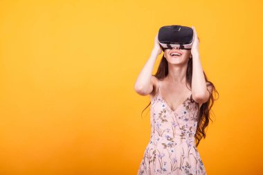 Mutlu kadın sanal gerçekliğin VR-kulaklık gözlük kullanma studio sarı arka plan üzerinde deneyim elde gülümse