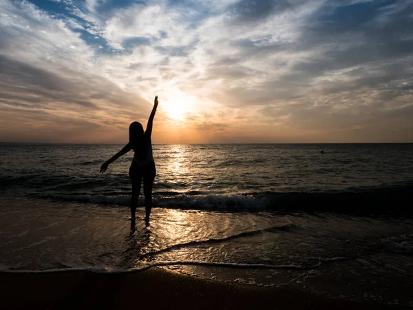 Silhouette di una giovane ragazza sulla spiaggia. giovane ragazza cammina al tramonto in riva al mare . — Foto Stock