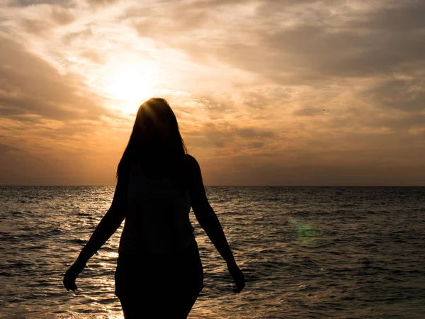 Silhueta mulher assistindo sol na praia ao pôr do sol — Fotografia de Stock