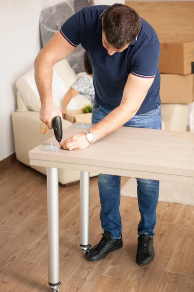 Uomo assemblaggio mobili nel loro nuovo appartamento — Foto Stock