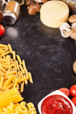 Çiğ çiğ spachetti ve vintage koyu arka plan üzerinde farklı ürünleri yanında makarna