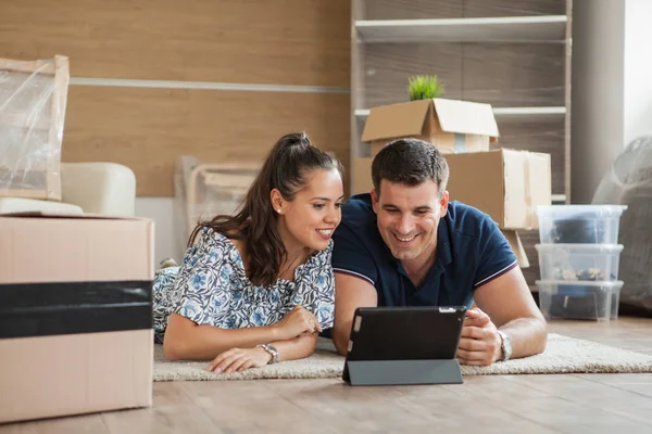 Decoración de planificación de pareja en línea con una tableta y mudanza a casa en la sala de estar — Foto de Stock