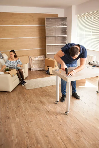 Man werkt met meubilair vergadering gebruik van elektrische schroevendraaier in nieuwe woning. — Stockfoto