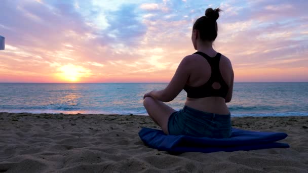 Junge Frau praktiziert Yoga am Strand bei Sonnenaufgang — Stockvideo