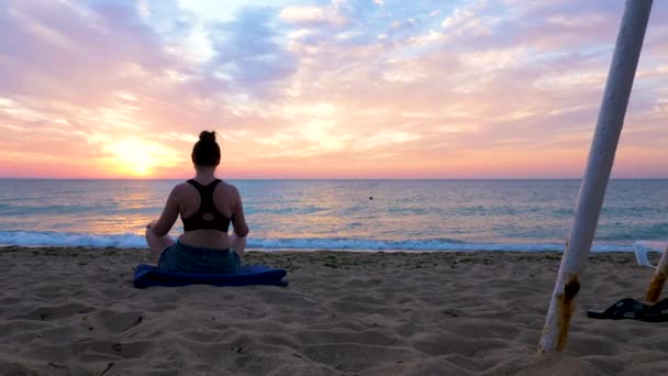 Мальовничі кадри жінки, що сидить у позі лотоса на пляжі — стокове відео