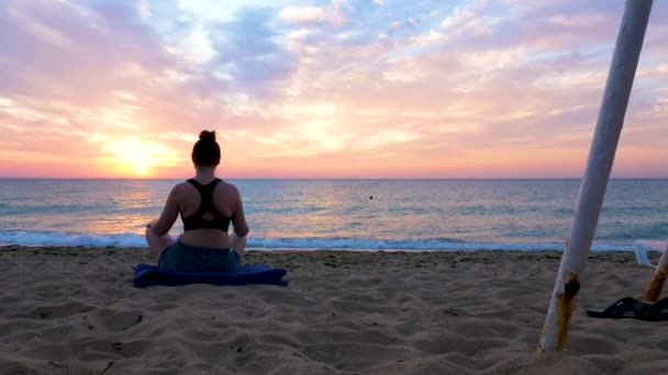 Mooie beelden van de vrouw in lotus houding zitten op het strand — Stockvideo