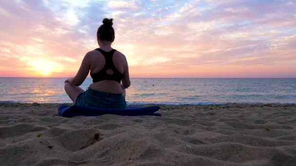 Woman practicing yoga on the beach at the sunrise looking at a scenig panorama — Stock Video