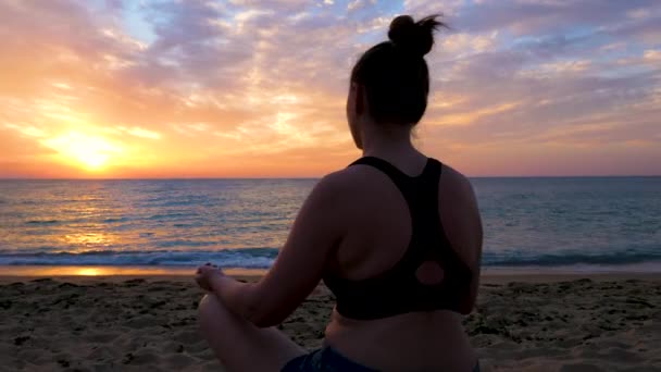 Silhueta de mulher sentada na praia praticando ioga — Vídeo de Stock