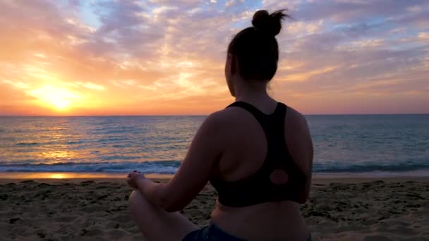 Silueta de mujer sentada en la playa practicando yoga — Vídeos de Stock