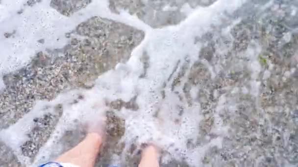 POV voeten in het water op het strand — Stockvideo