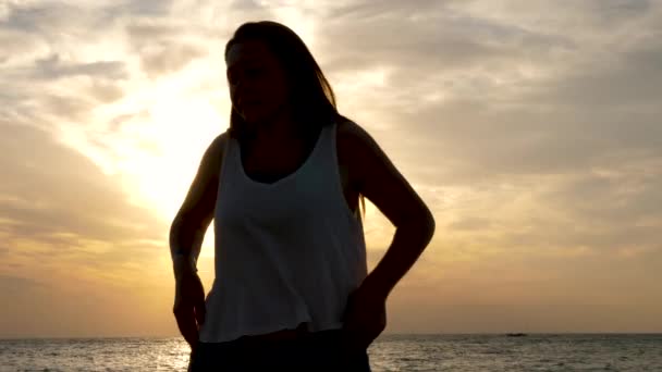 Silhouet van de vrouw aan de zee met een prachtige sceninc zonsopgang achter — Stockvideo