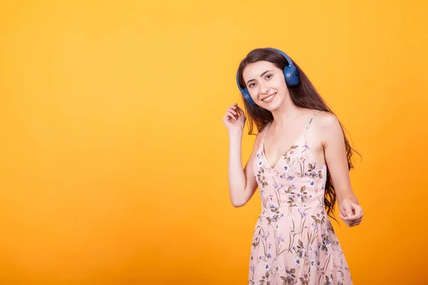 Bonito jovem mulher ouvir música no estúdio a partir de ela headpshones no amarelo fundo — Fotografia de Stock