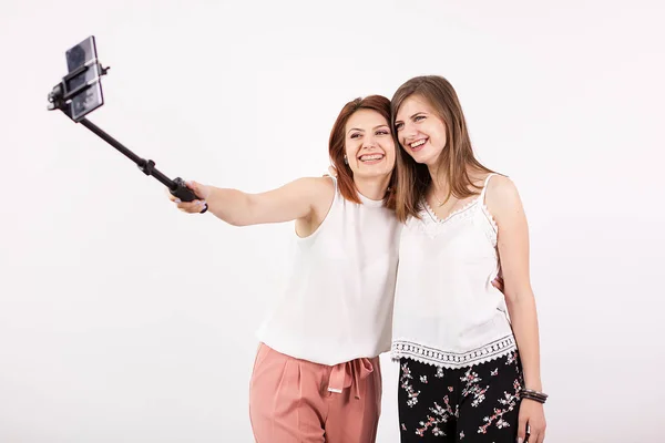 Deux belles jeunes femmes prenant un selfie avec un bâton de selfie — Photo
