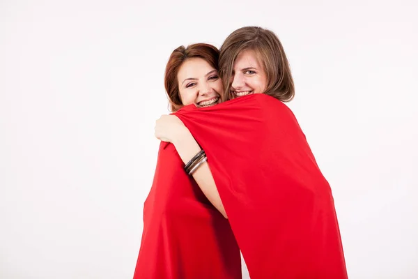 Deux belles amies qui se couvrent avec une couverture rouge — Photo