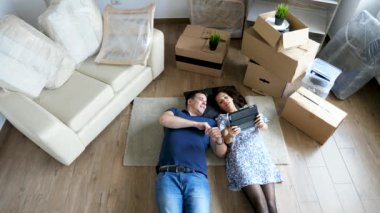 Mutlu çift karton kutuları ile çevrili onların yeni apartman dairesinde uzanarak