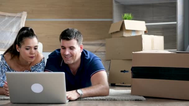 Par liggande på golvet i sitt nya hem shopping online — Stockvideo