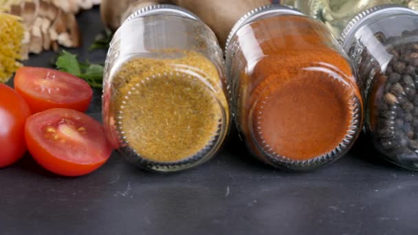 Different spices in glass jars next to sliced tomatoes and tomato souce — Stock Video