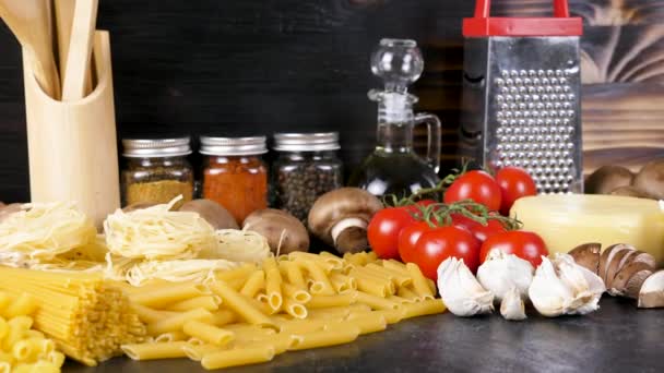 Variedad de pasta cruda en la mesa junto a otros ingredientes para la cena — Vídeo de stock