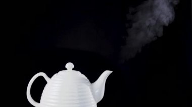 Çay potu kaynar su ile siyah arka plan üzerine