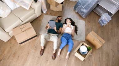 Sevgi dolu bir çiftin tablet kullanarak yerde yatarken üstten görünüm