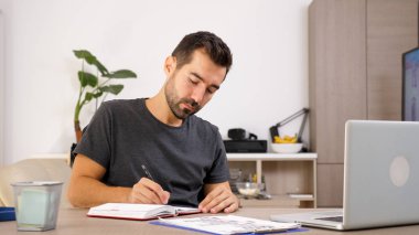 Adam onun masasında dizüstü yazma.