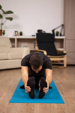 Paschimottanasana yoga poz yapıyor katta oturan genç adam