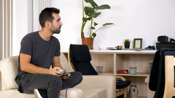 Attractive young man sitting on his couch and playing video games — Stock Photo, Image