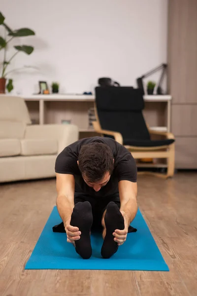 Молодий чоловік сидить на підлозі робить позу Пасімоттанасанії йоги — стокове фото