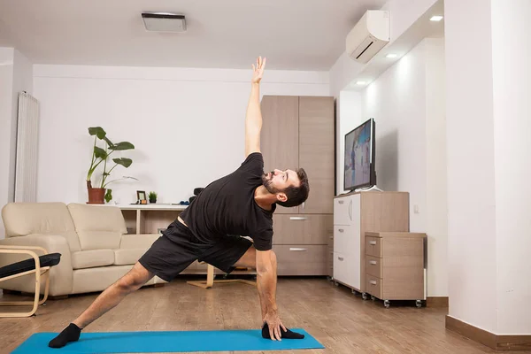 Aantrekkelijke man probeert uitgebreide kant Yoga vormt op de vloer van zijn huis — Stockfoto