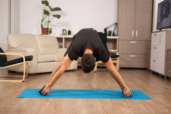 Staande voorwaartse yoga pose gemaakt door pasvorm volwassen op de vloer van zijn huis — Stockfoto