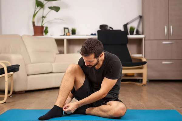 Jonge man praktizerende yoga in zijn woonkamer — Stockfoto