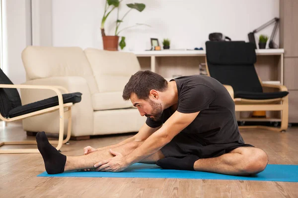 Jonge man praktizerende yoga in zijn woonkamer — Stockfoto
