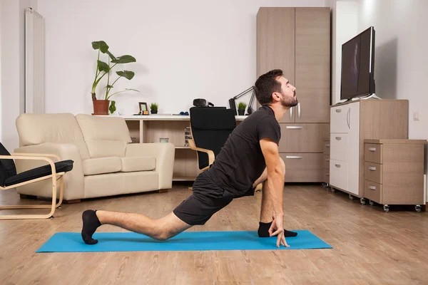 Man in zijn 30s doet yoga op een matras in zijn huis past — Stockfoto