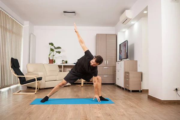 Aantrekkelijke man probeert uitgebreide kant Yoga vormt op de vloer van zijn huis — Stockfoto