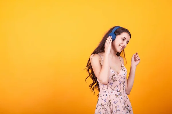 Bonito jovem ouvindo música em seus fones de ouvido em estúdio sobre fundo amarelo — Fotografia de Stock