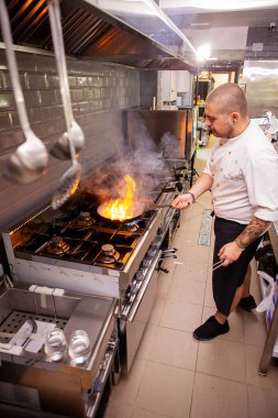 Yiyecek hazırlama. Şef aşçı bitti soba yapıyor pan ile mutfakta flambe.