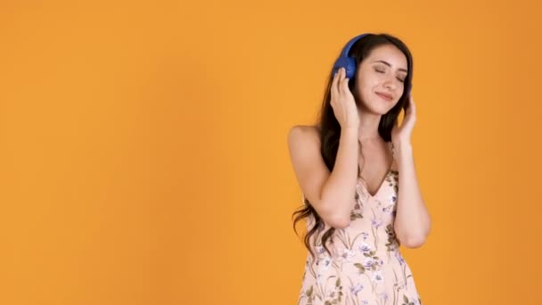 Όμορφη νεαρή κοπέλα στο φόρεμα του καλοκαιριού ακούγοντας musicv — Αρχείο Βίντεο