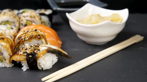 Mischung aus verschiedenen Sushi-Rollen auf schwarzem Stein Hintergrund — Stockvideo